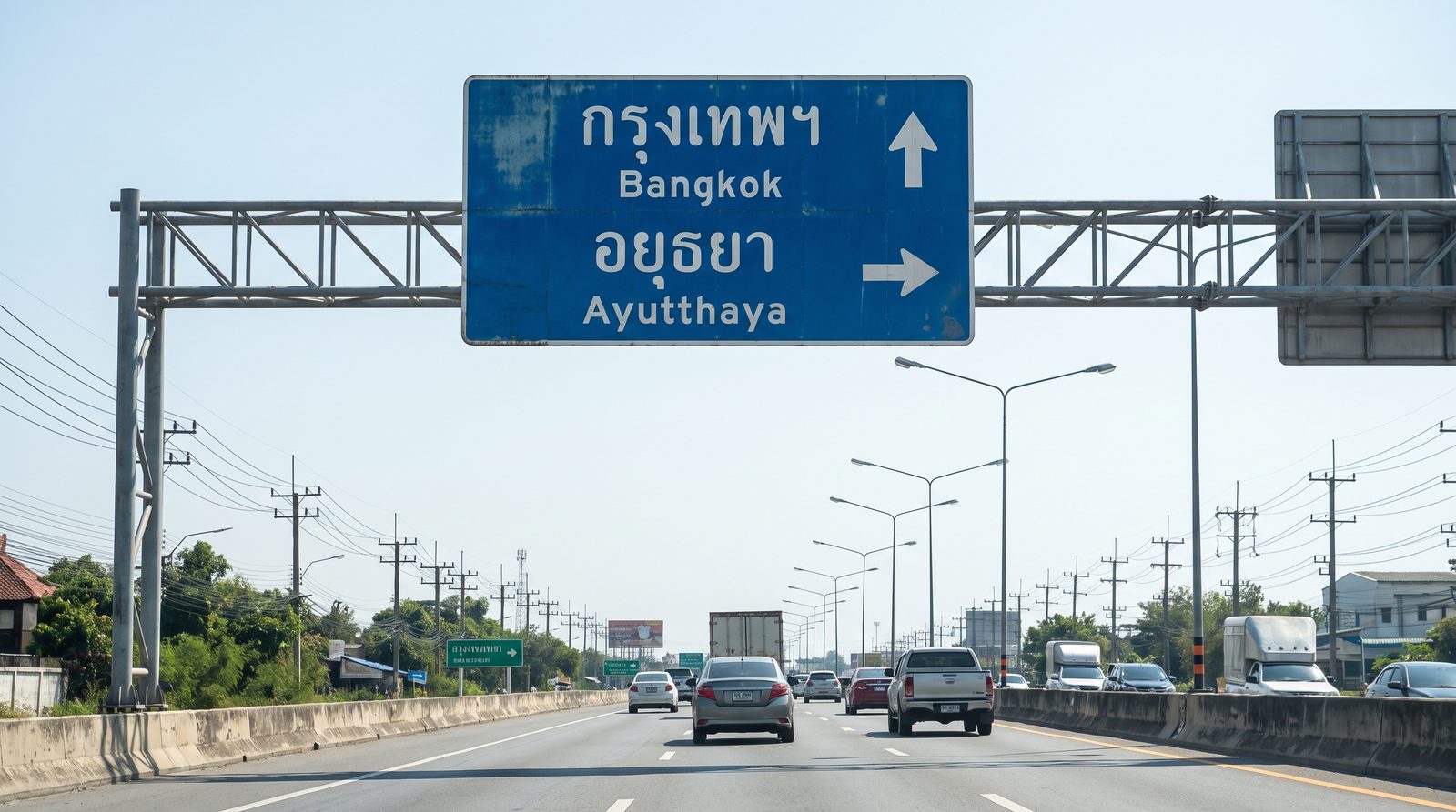Blue Thai motorway sign showing กรุงเทพฯ (Bangkok) above อยุธยา (Ayutthaya), an everyday example of reading Thai script on road signs