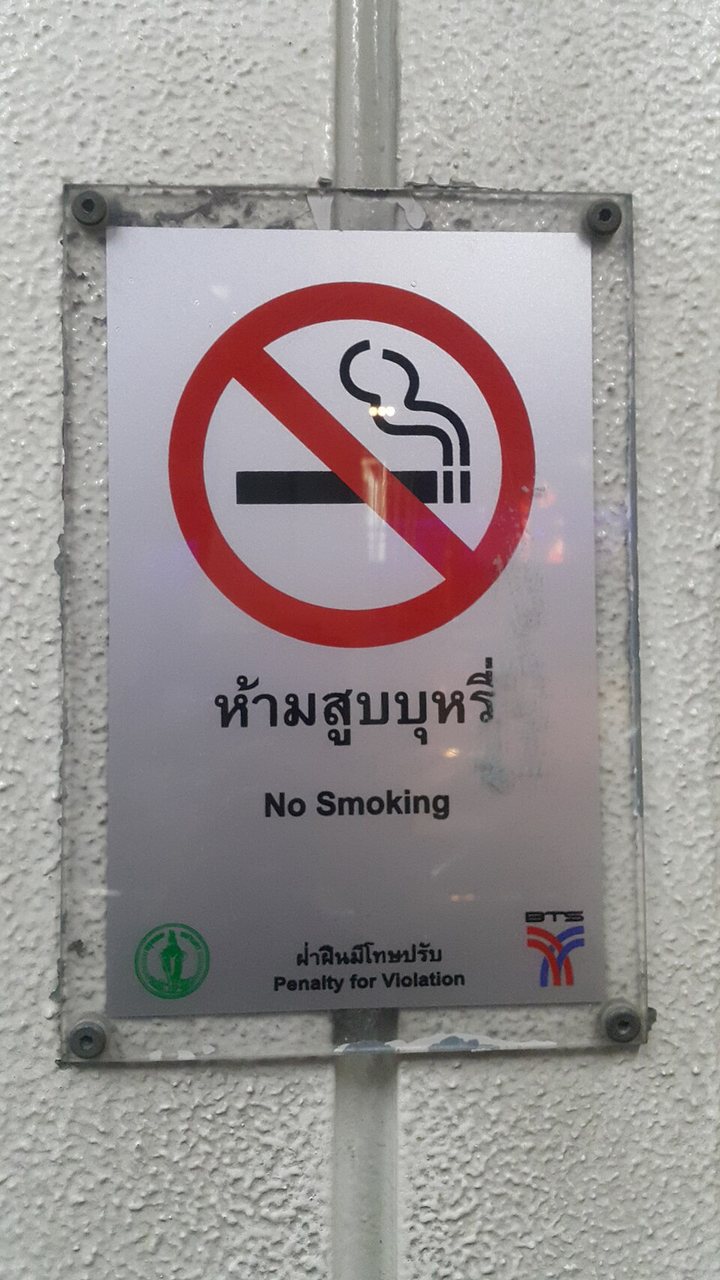 No-smoking sign at a BTS Skytrain station in Bangkok with Thai text ห้ามสูบบุหรี่ and ฝ่าฝืนมีโทษปรับ