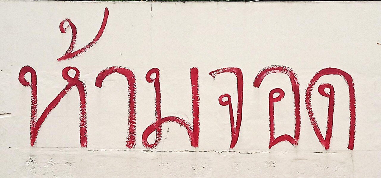 Hand-painted red Thai sign reading ห้ามจอด (hâam jɔ̀ɔt, 