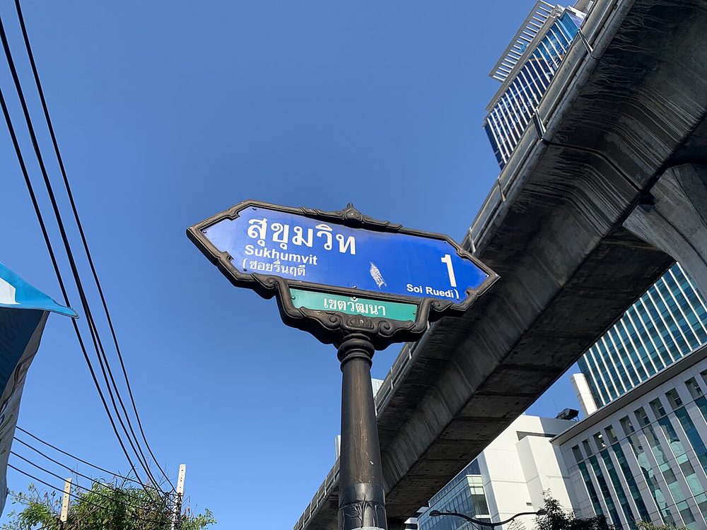 Blue Bangkok street sign showing สุขุมวิท Sukhumvit and the soi name ซอยรื่นฤดี Soi Ruedi in Thai script and English transliteration