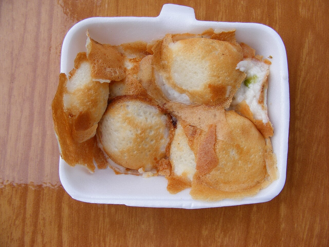 Foam container of Thai khanom krok coconut pancakes, browned at the edges and pressed together in pairs