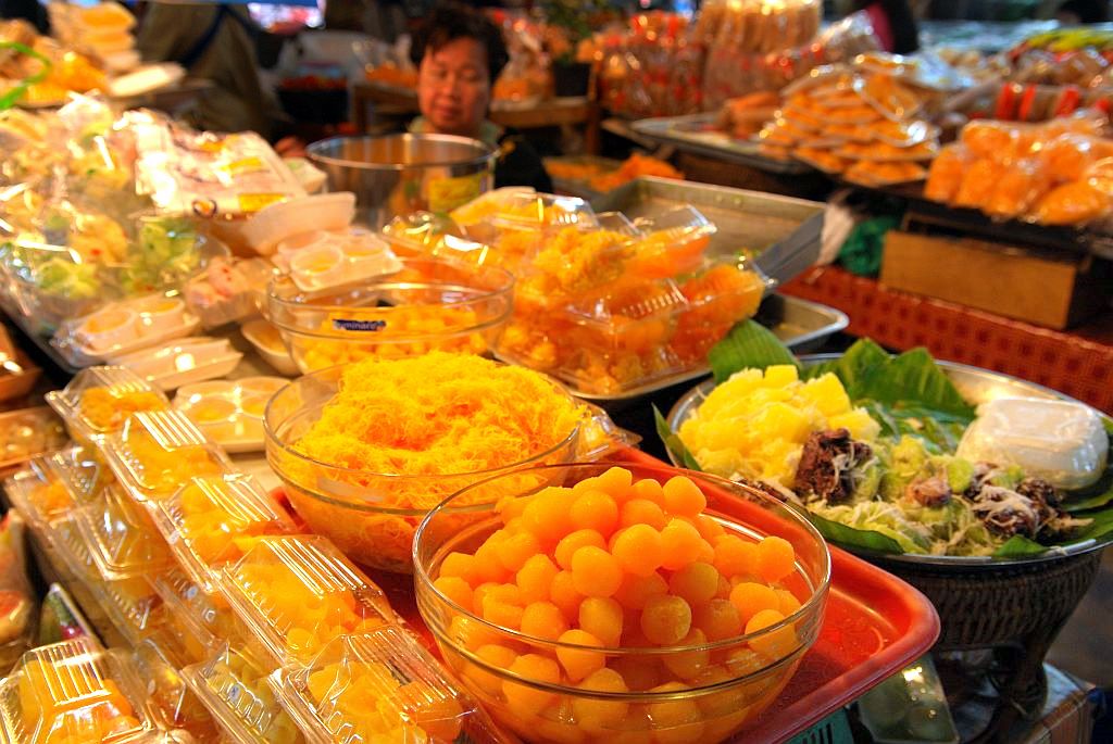 Thai market dessert stall in Chiang Mai with bowls of golden thong yot balls, shredded foi thong and packets of Thai sweets