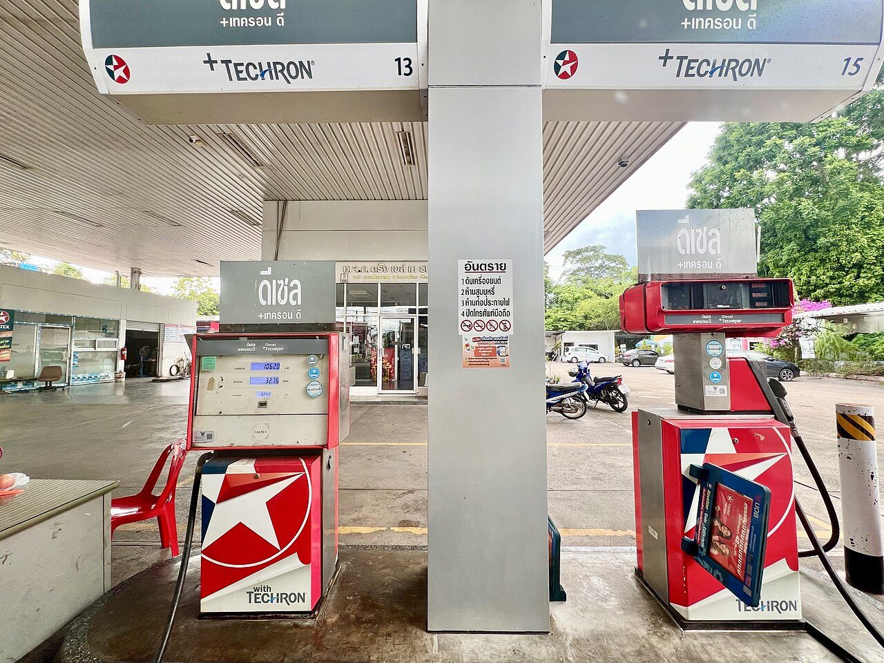 Fuel pumps at a Caltex station in Trang, Thailand, labelled diesel in Thai script beside a Thai safety notice