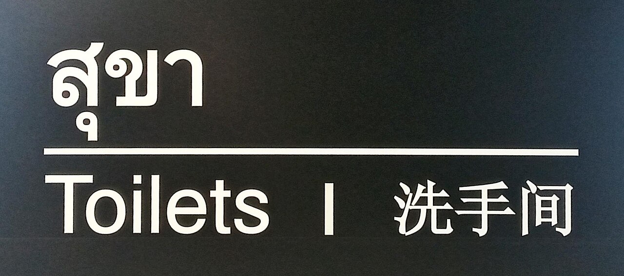 Trilingual Thai toilet sign reading sukha in Thai script above the English word Toilets and Chinese characters