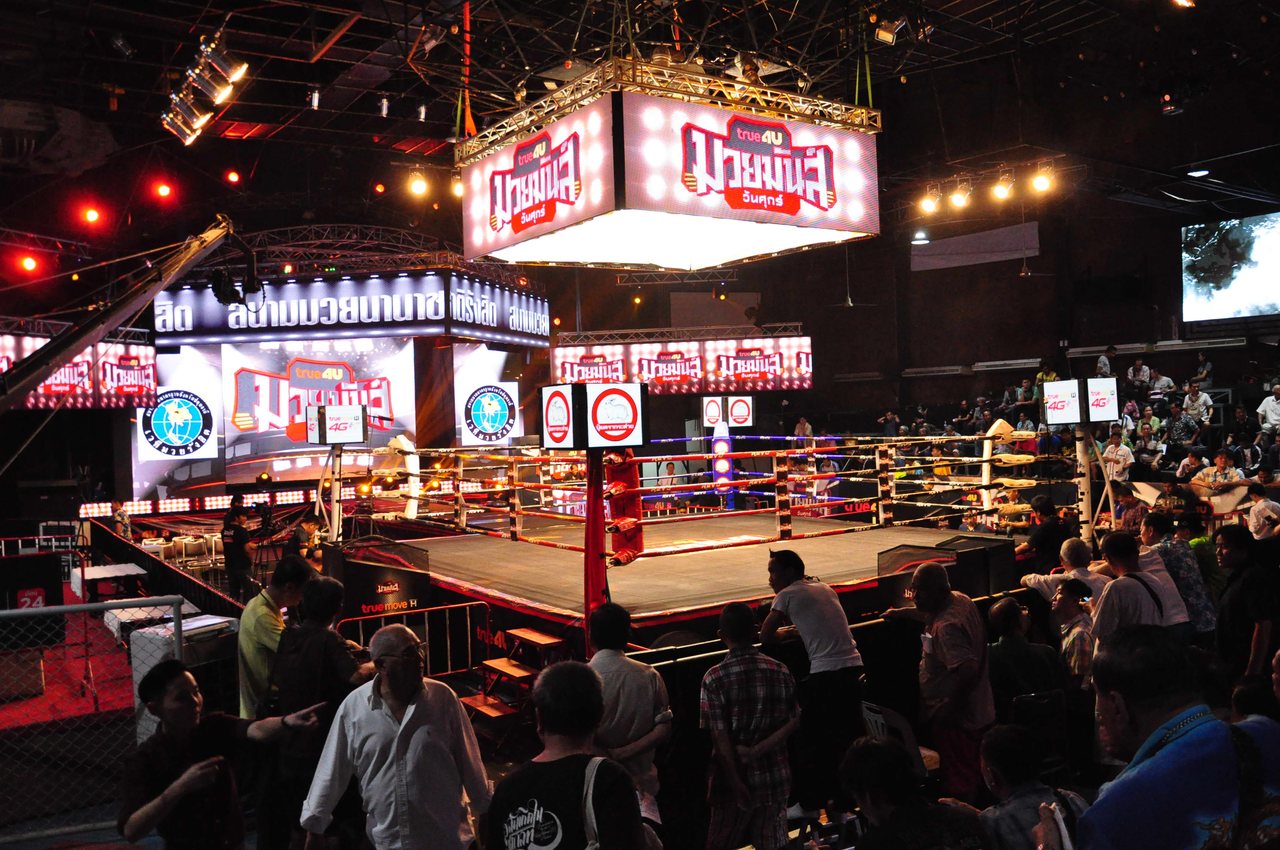 Muay Thai ring in a Thai boxing stadium with LED screens showing Thai letters reading muay man wan suk above the ropes