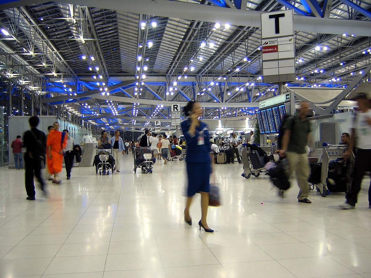 Departures hall at Suvarnabhumi Airport in Bangkok Thailand with check-in row letters and a flight information board showing Thai and English