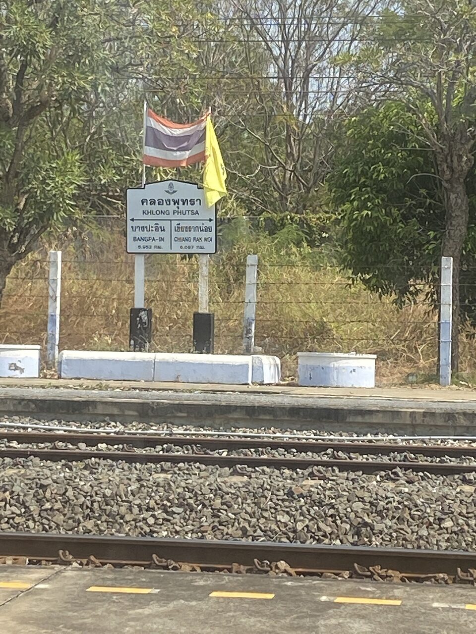 Thai railway station nameboard reading khlong phutsa in Thai script with neighbouring stations Bang Pa-in and Chiang Rak Noi and distances in kilometres