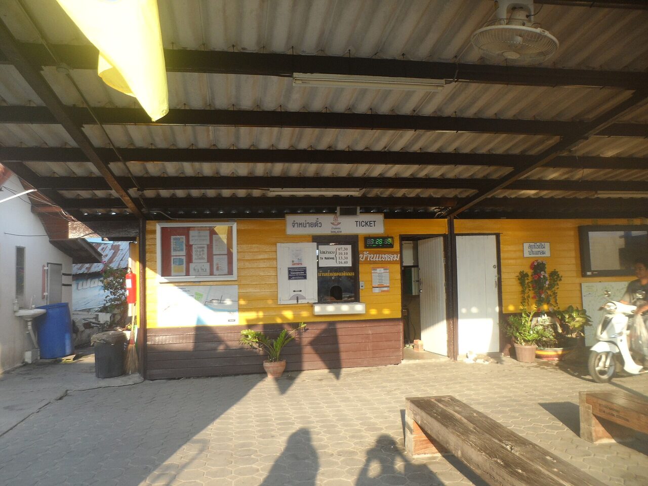 Wooden ticket window at Ban Laem railway station Thailand with a Thai sign reading jamnai tua ticket and departure times to Mae Klong