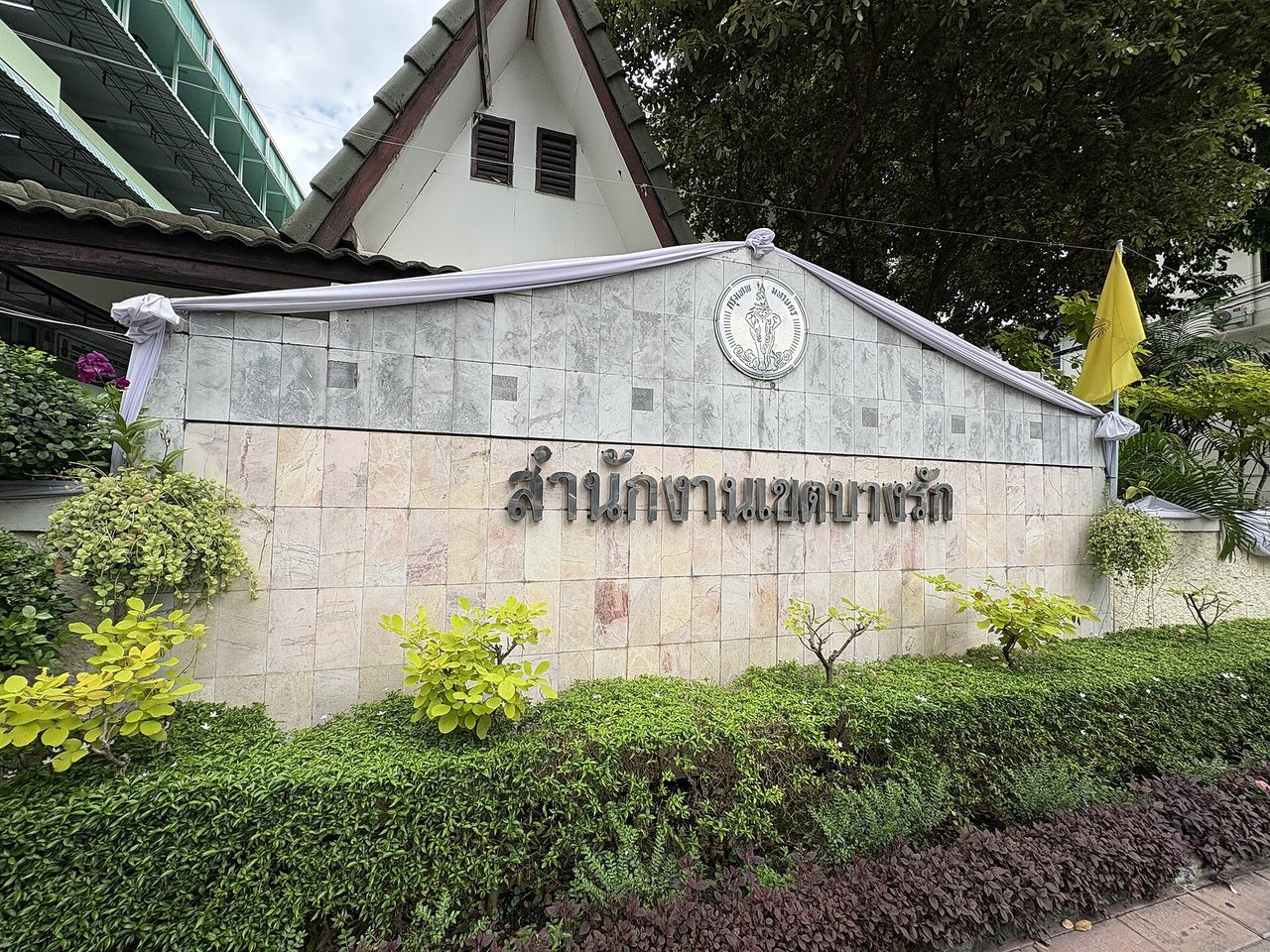 Bang Rak District Office sign in Bangkok Thailand with large Thai script reading samnakngan khet Bang Rak in raised metal letters