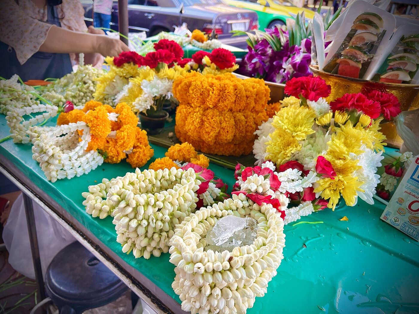Close up of fresh Thai jasmine phuang malai garlands with marigold roses and ice on a market table in Bangkok Thailand