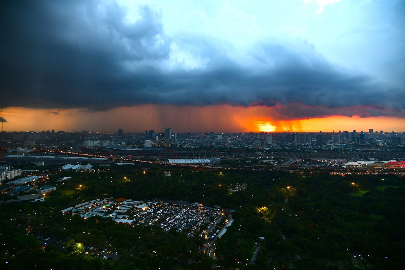 Monsoon rain storm with visible rain curtain falling over the Bangkok skyline at sunset in Thailand, used to learn Thai vocabulary for rain and weather