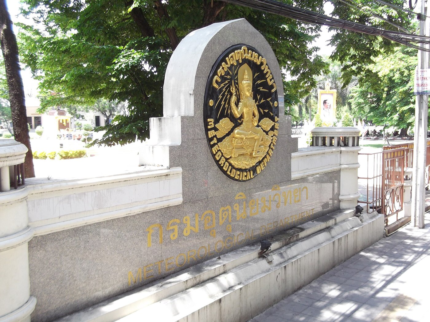 Gold Thai script sign reading krom utuniyomwitthaya outside the Thai Meteorological Department in Bangkok Thailand with English transliteration underneath