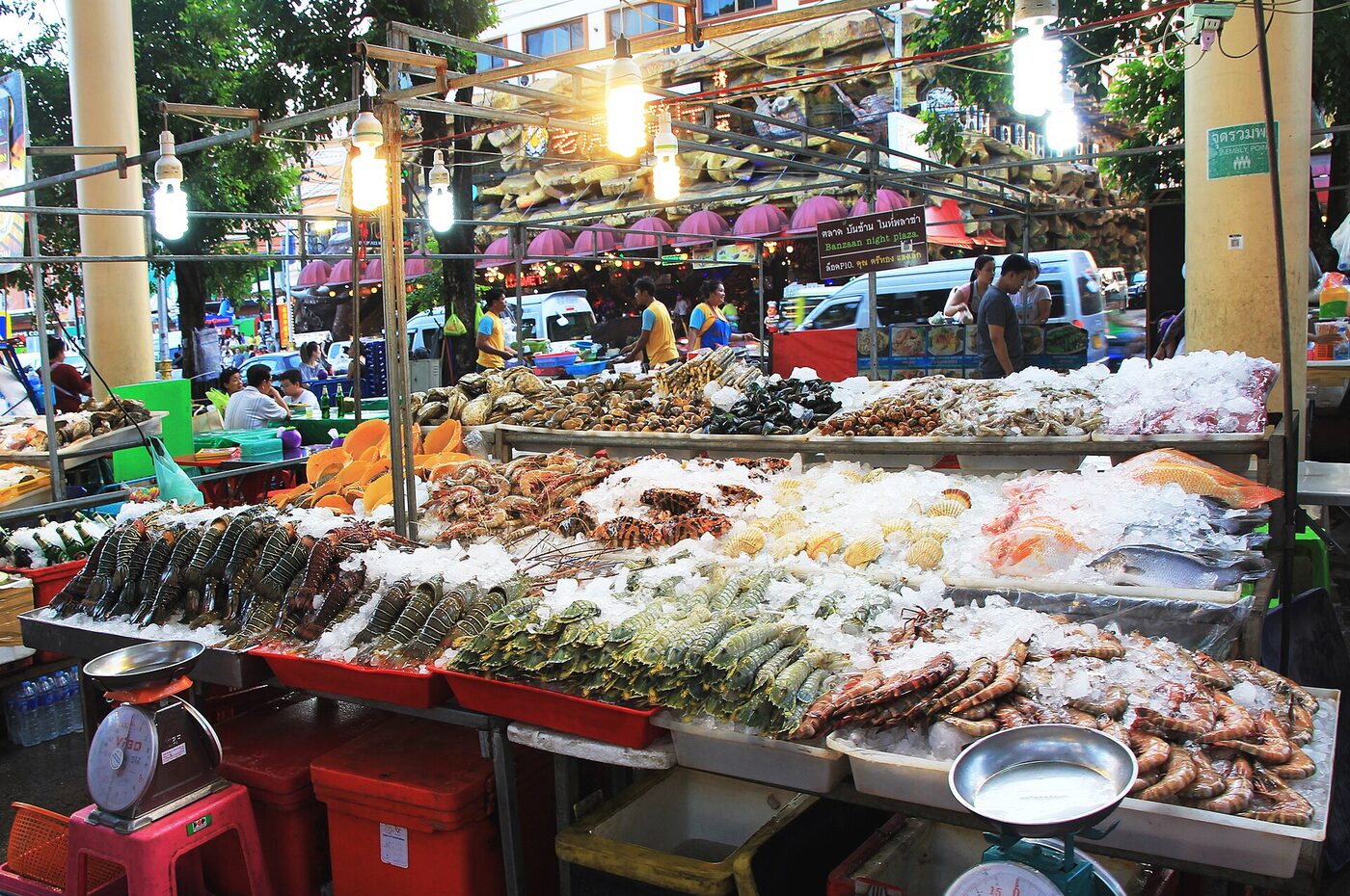 Thai seafood market stall in Patong, Phuket, piled with prawns, lobster, shellfish and fish on ice under a Thai-language market sign