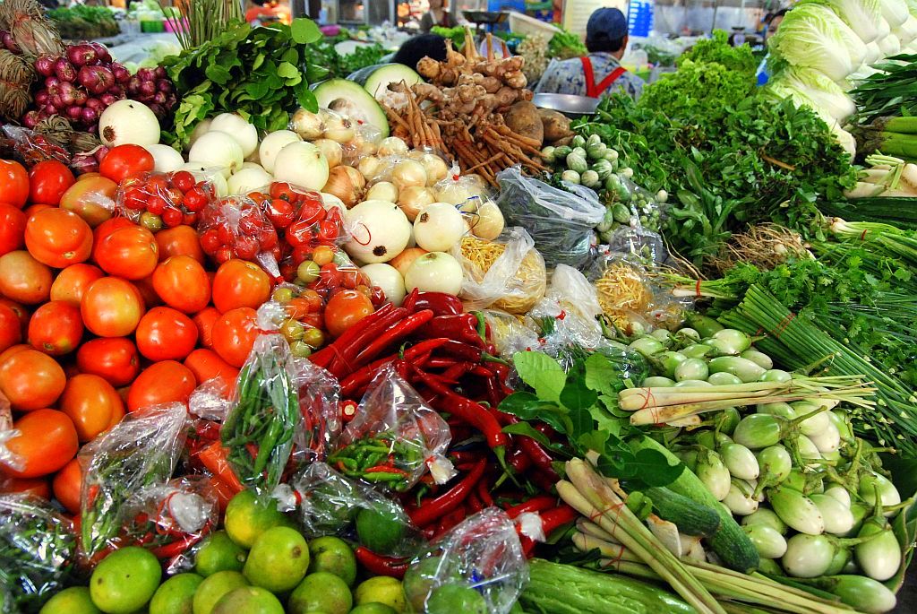Fresh Thai vegetables and herbs on a market stall in Chiang Mai Thailand with tomatoes red chillies lemongrass limes and Thai eggplant, used to learn Thai vocabulary