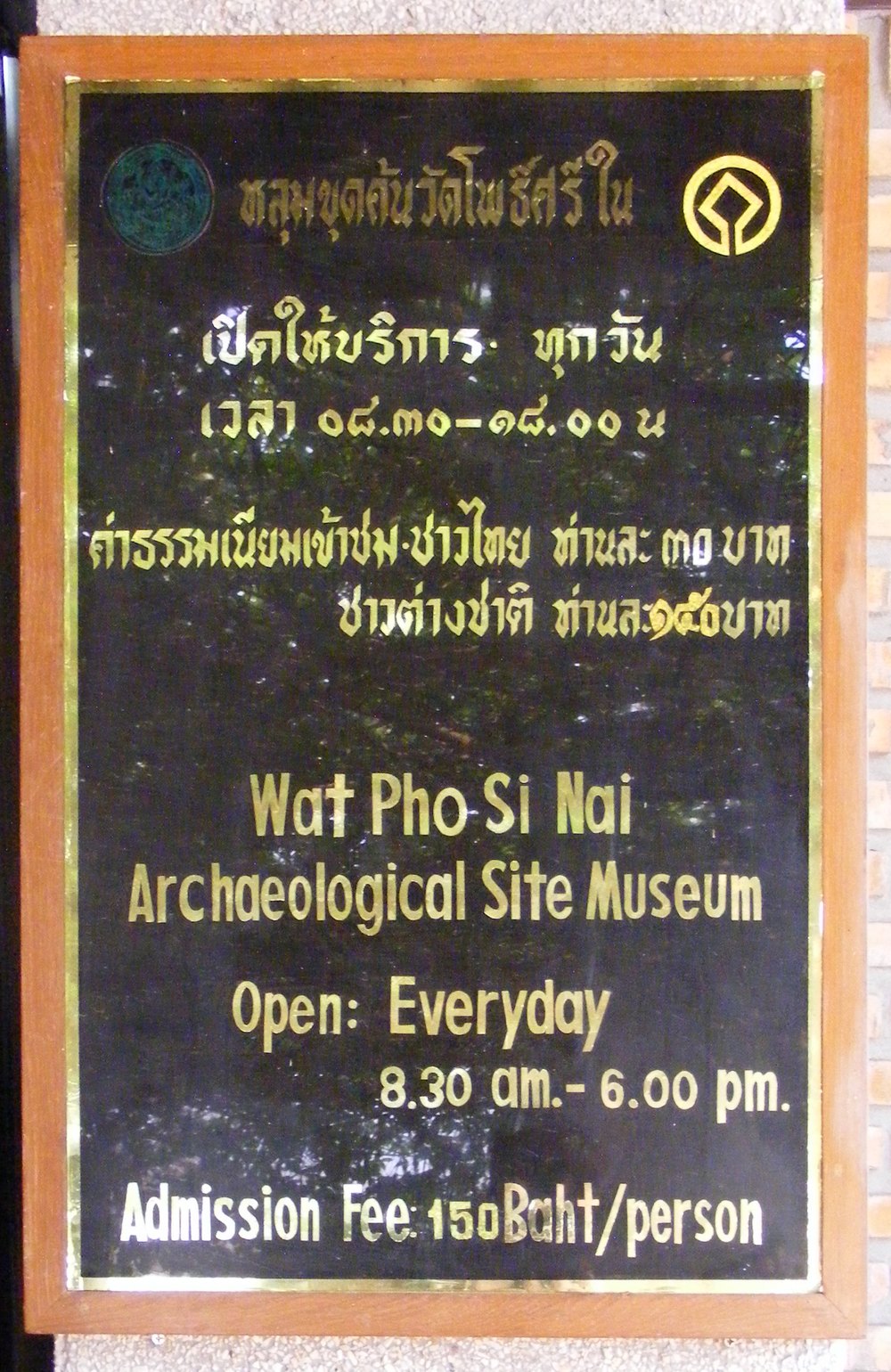 Gold on black Thai script sign at Wat Pho Si Nai Ban Chiang Thailand showing opening hours in Thai numerals and separate entry fees for Thai and foreign visitors