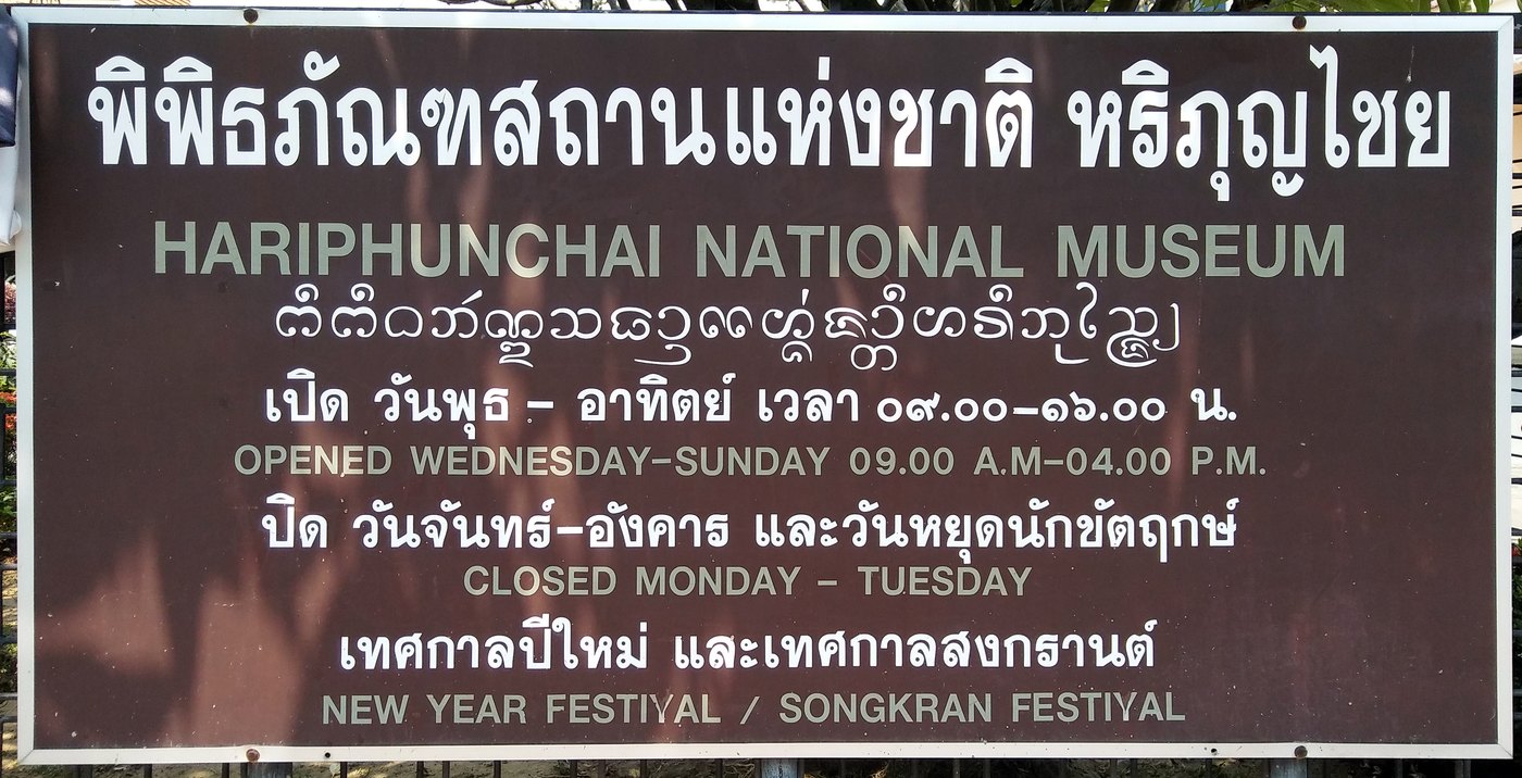 Brown opening hours sign in Thai script at Hariphunchai National Museum in Lamphun Thailand showing open Wednesday to Sunday and closed Monday Tuesday, used to learn to read Thai script