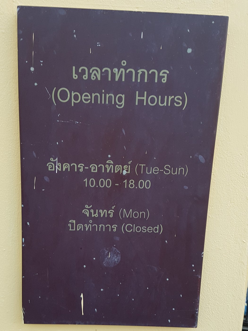 Thai language opening hours plaque reading wela tham kan at Museum Siam in Bangkok Thailand listing Tuesday to Sunday 10.00 to 18.00 and closed Monday