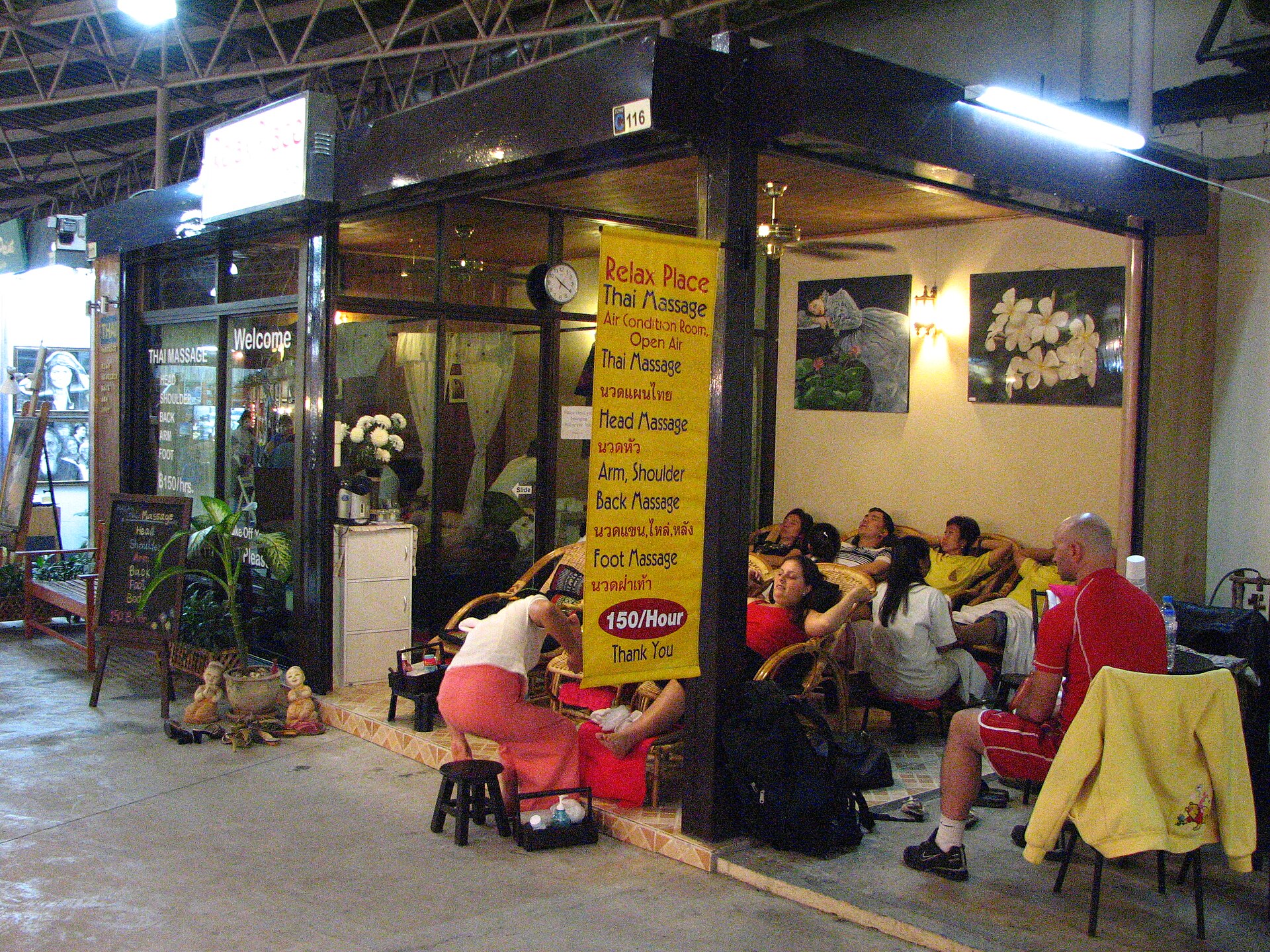 Yellow Thai massage shop banner in Chiang Mai listing nuat phaen thai nuat hua nuat khaen lai lang and nuat fa thao in Thai script with prices