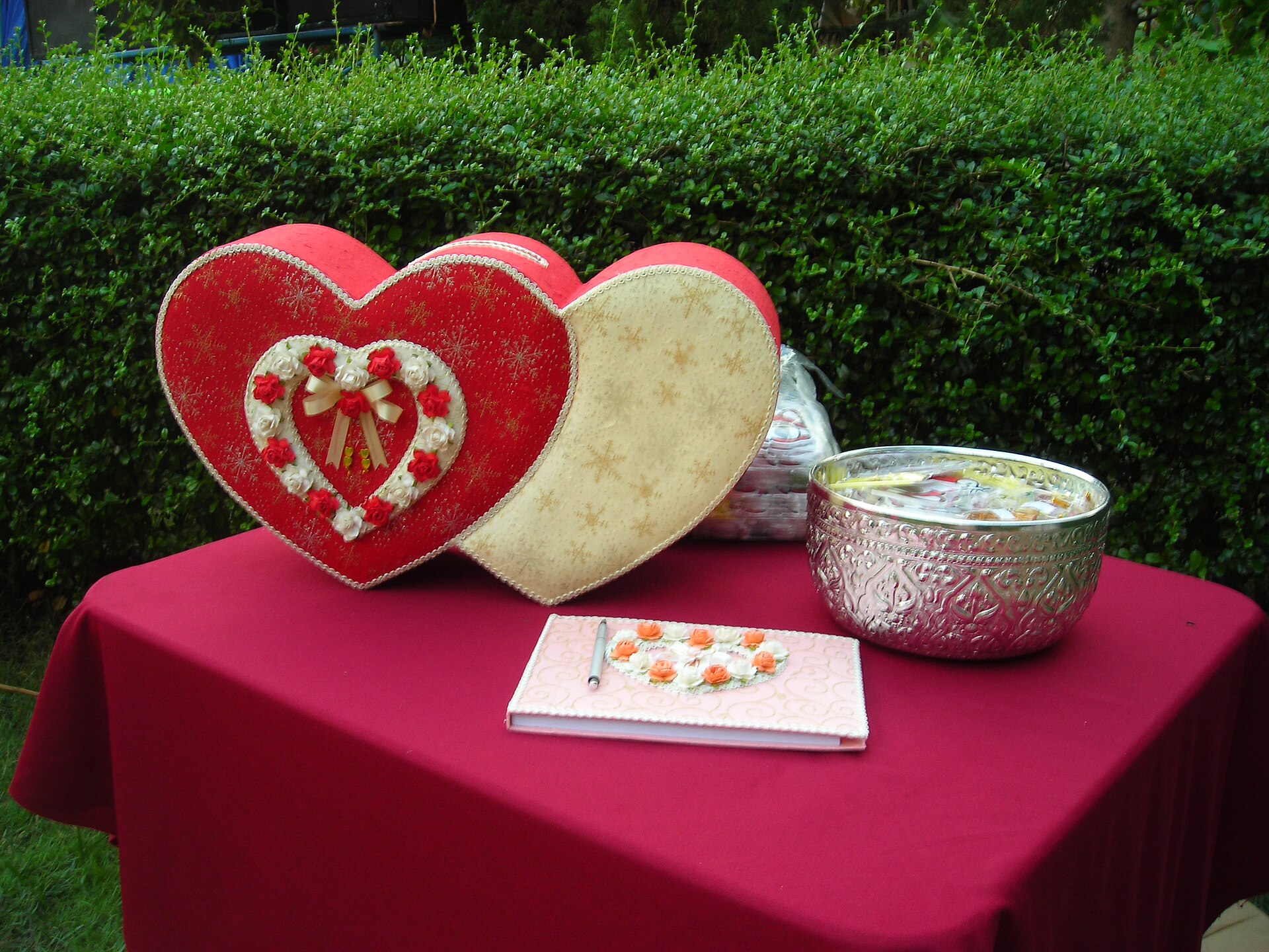 Thai wedding reception desk with a double heart envelope box blessing book and silver bowl for guests at a wedding in Thailand